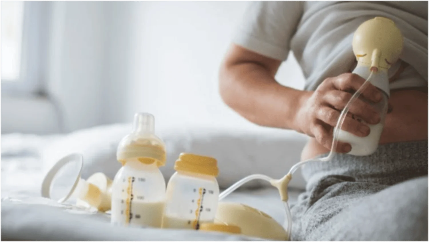 Madre extrayendo leche con un extractor Medela junto a biberones con leche materna